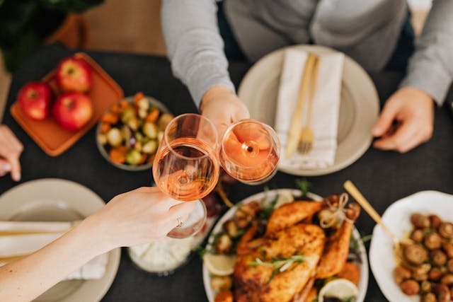 two people clicking glass wine over Christmas dinner