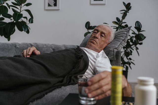 elderly man lying sick on couch