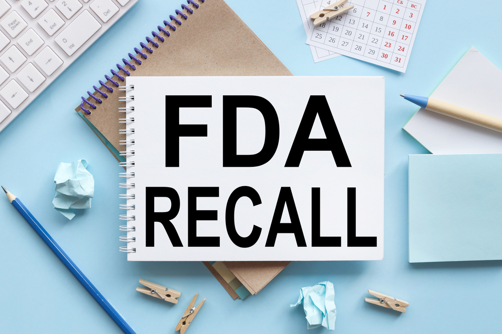 FDA recall. text on white notepad paper on blue background. near stickers, magnifying glass, white keyboard, calendar