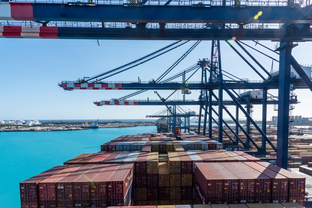 Freeport, Bahamas - April 15, 2023: view on the containers loaded on deck of the cargo ship. She is berthed under gantry cranes for loading and unloading cargo on her international route.