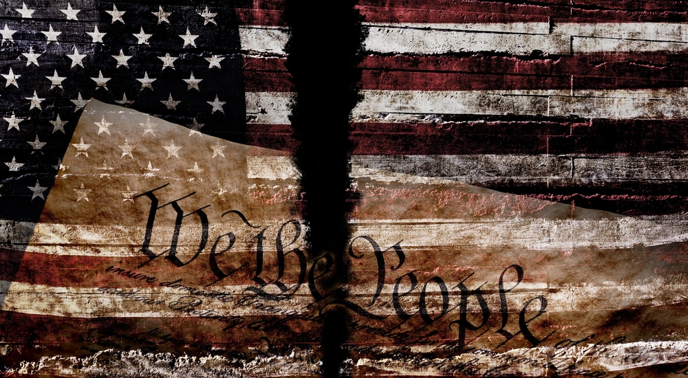 Distressed American flag and the US Constitution torn in two representing division in US politics and the threat to democracy and the 2024 election                             