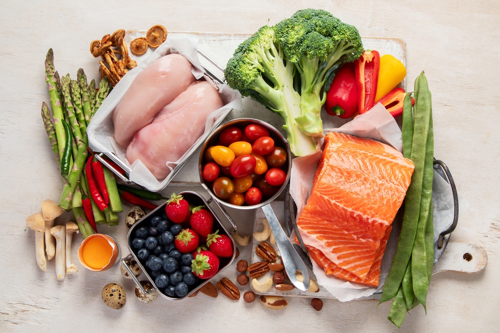 Ketogenic diet food. Healthy low carbs products. Keto diet concept. Vegetables, fish, meat, nuts, seeds, berries, cheese on a white background, top view.