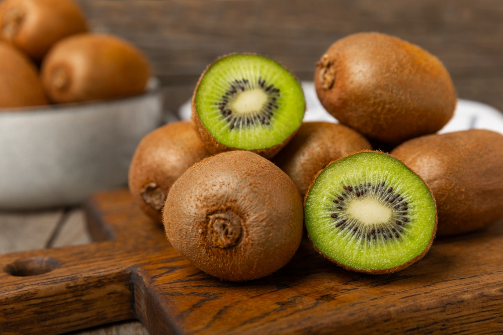 Kiwi on wooden background. Whole fruit and slices pieces of green kiwi on table. fresh ripe juicy kiwi. Tropical fruit. Organic fruit. Healthy eating. Space for text. Copy space.