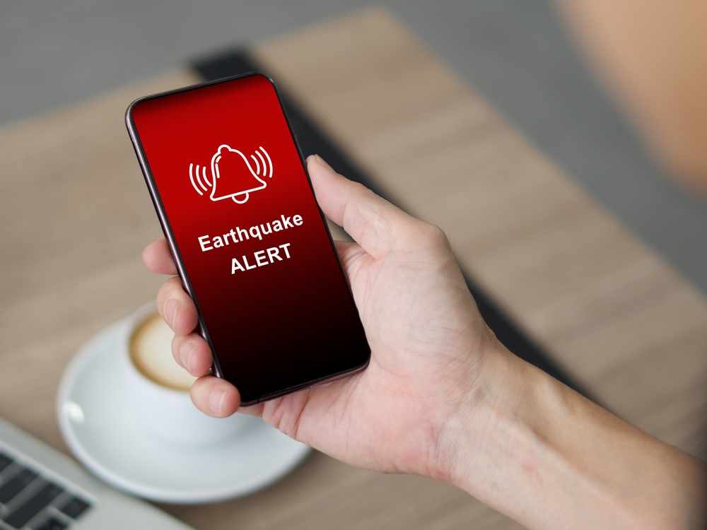 Earthquake alert warning displayed on smartphone screen as symbol, telling people to be careful. Technology concept