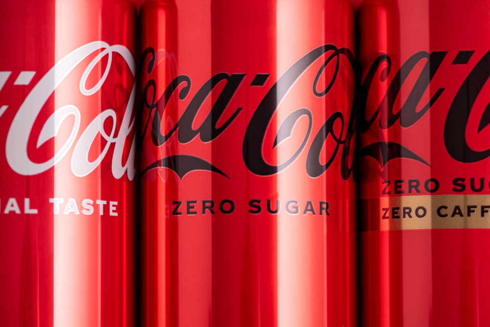 Lviv, Ukraine - May 05, 2025: Set of iron cans of drink Coca Cola: classic, zero sugar, zero sugar zero caffeine, cherry flavor on red background. Top view