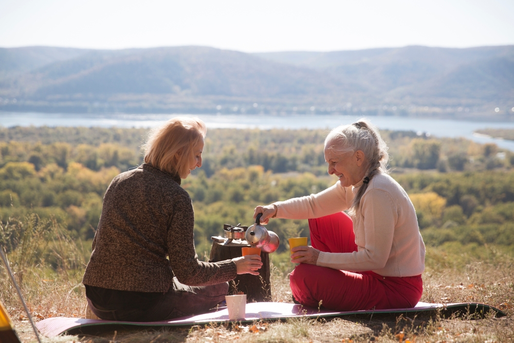 two women relaxing in the mountain and brew coffee in Geyser coffee maker on a sunny autumn day. Mindfulness and feel-good moments. spends time in nature. adult camp