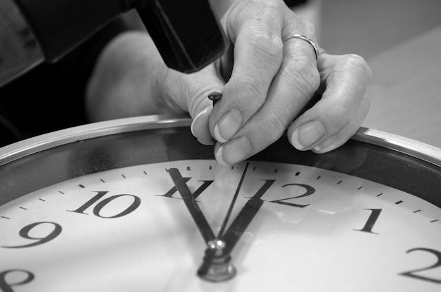 person hitting a nail into a clock