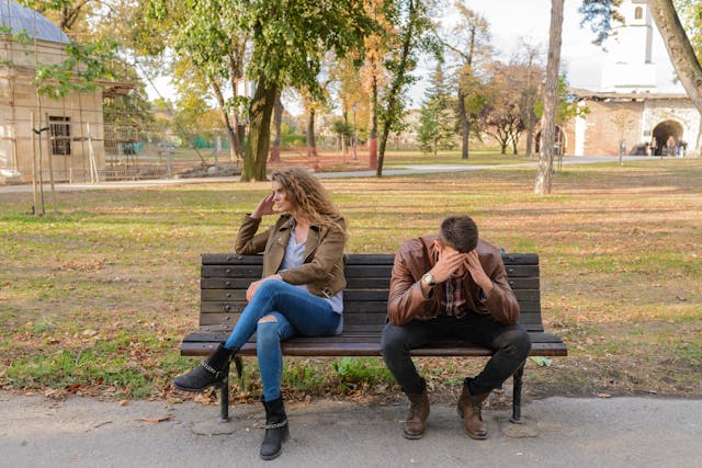 unhappy couple sitting on a bench in a park