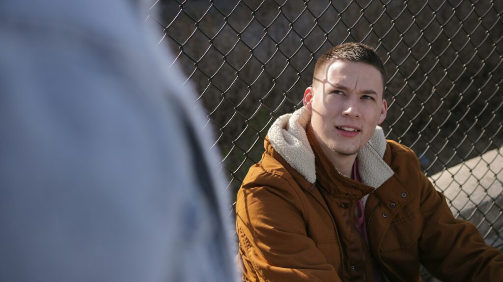 man sitting near fence