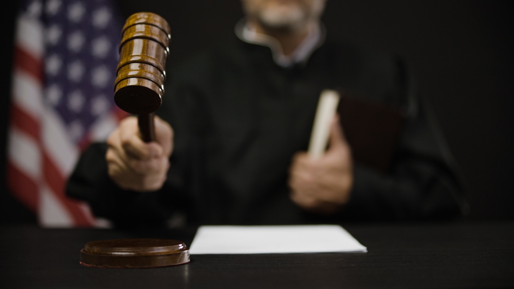 Male judge hitting gavel, calling court members to stand, United States justice system