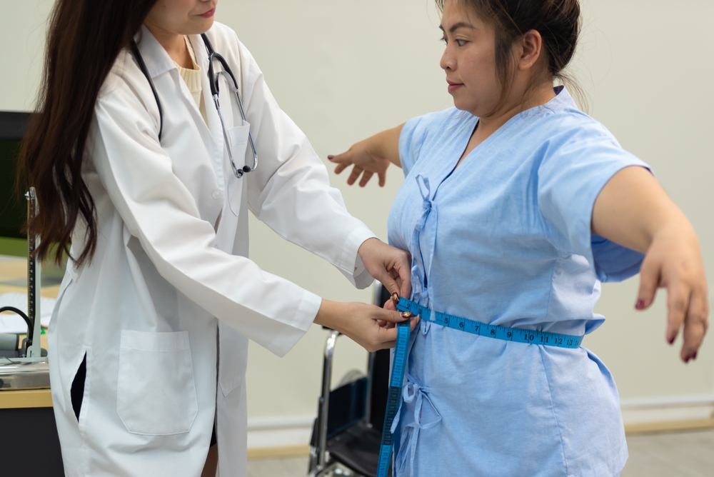Asian female doctor checking a fat woman's body at hospital.
