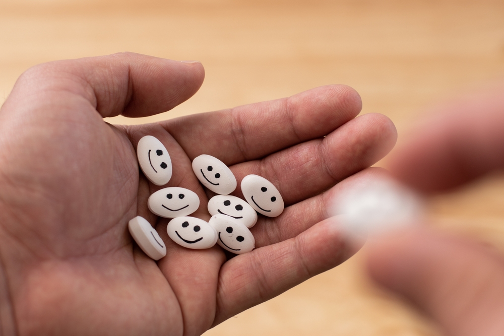 Hand taking a white medicine pill with happy face focus in the pills with bokeh background