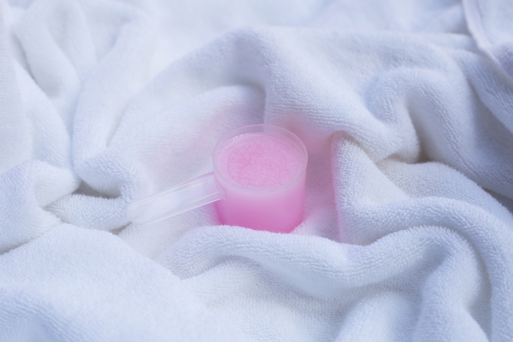 Fabric softener in measuring spoon on towel. Laundry concept.