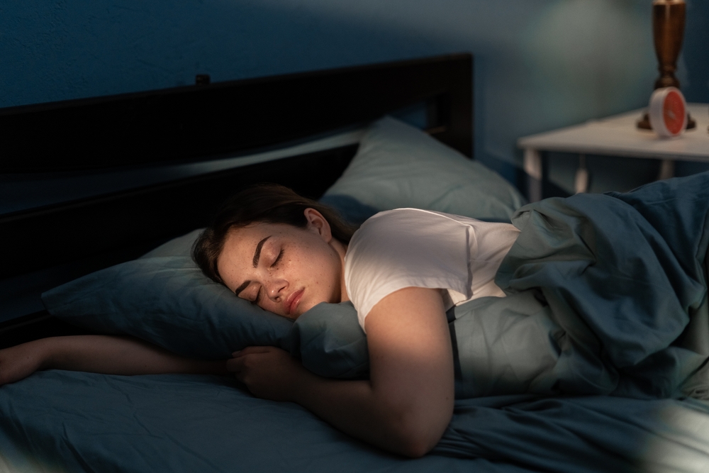 Young female sleeping peacefully in her bedroom at night. Relaxing at nighttime. Copy space