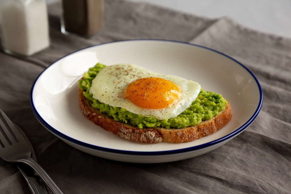 Homemade Avocado Toast with Egg on a Plate, side view.