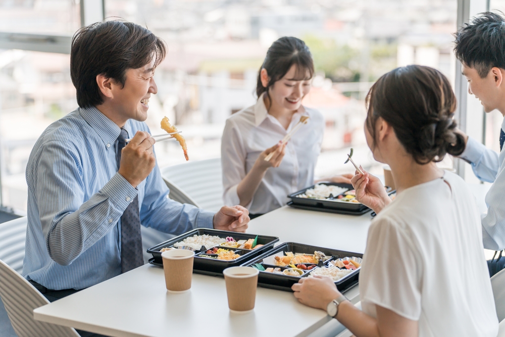 Men and women eating lunch, catered lunch, delivery lunch, or catered lunch in the company cafeteria (employee benefits)
