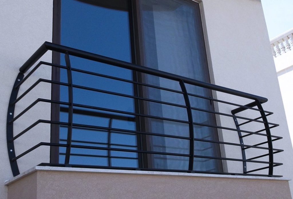 A balcony with bars and a glass door. Curtains and white walls in the background.