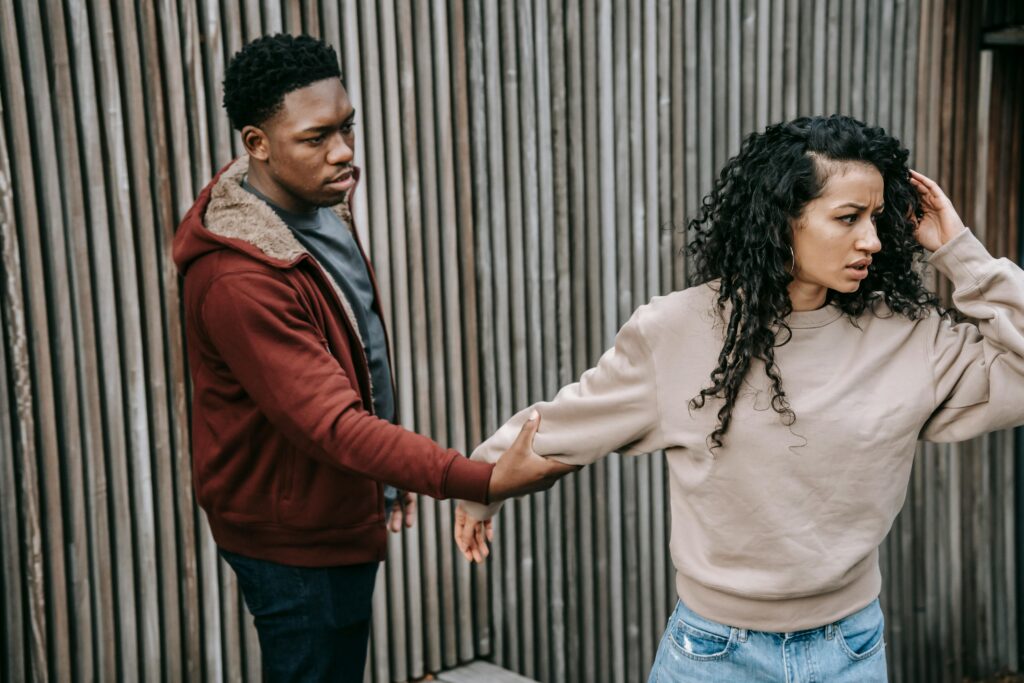 Black man grabbing hand of insulted ethnic woman