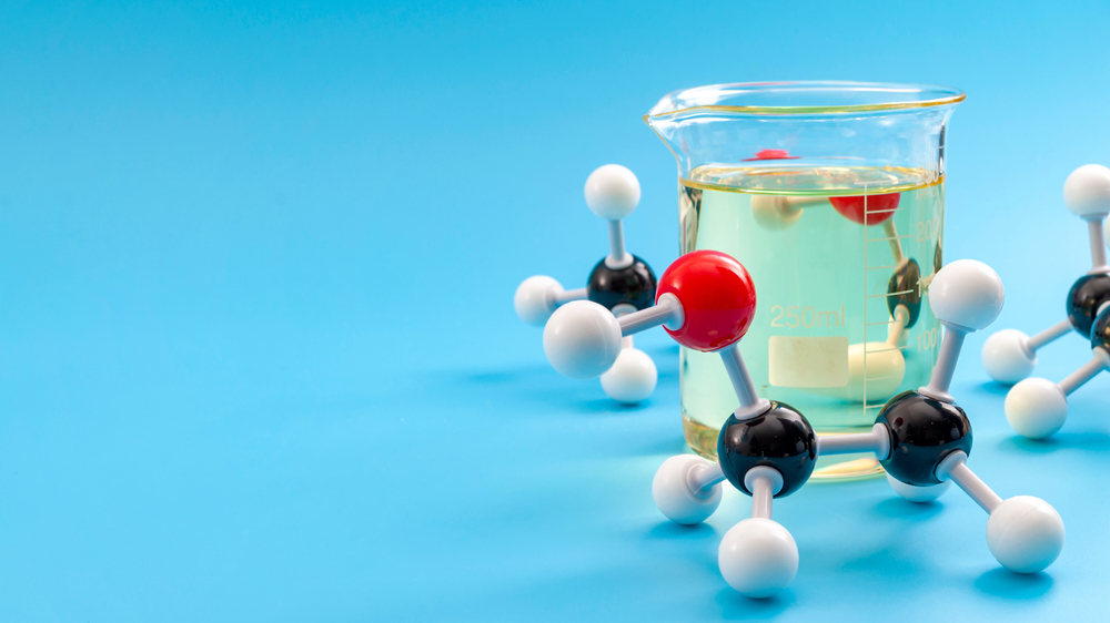 Molecular structure of chemical compounds and organic chemistry concept with educational plastic model of ethanol molecules and glass flask isolated on blue background with copy space
