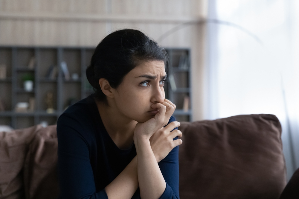 Thoughtful stressed young Indian ethnic woman looking in distance, considering psychological problem solution, suffering from depression or feeling doubtful making difficult decision at home.