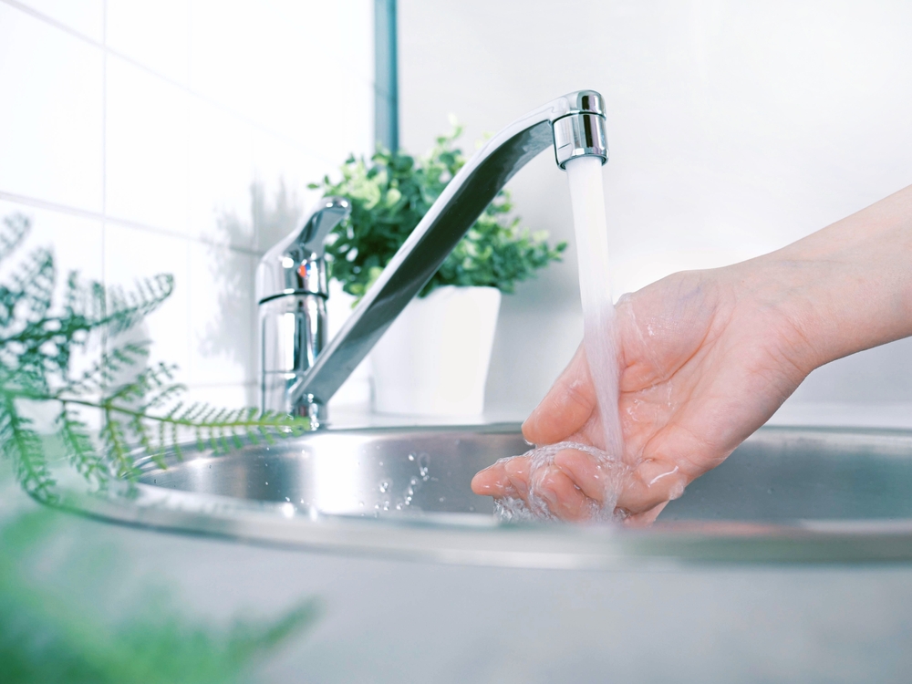 A stream of clean water drink flows into human hands. Wash hands and hygiene. Water consumption, environment, water pollution and water scarcity concept