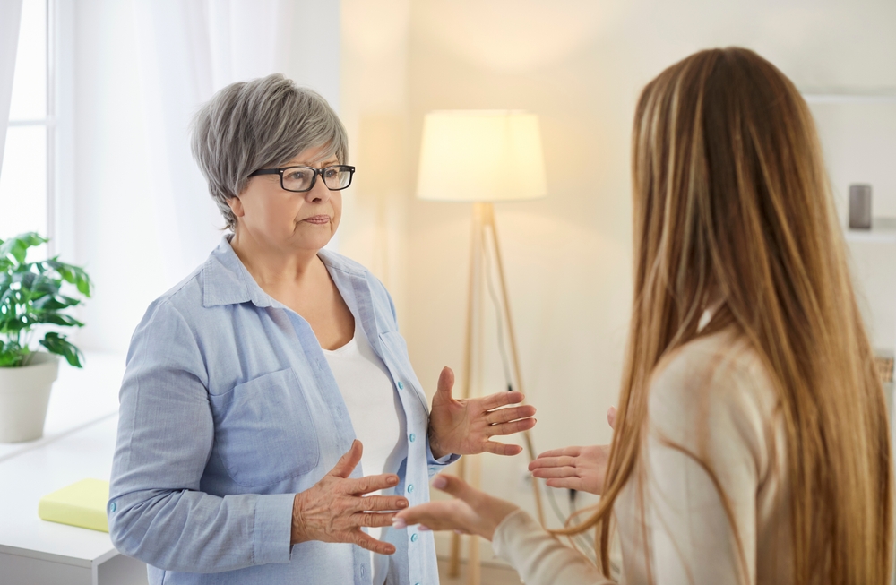 Unhappy elderly woman gesturing and explaining something to young woman during conflict. Frustrated senior mother and her adult daughter facing with misunderstanding between different generations.