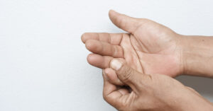 person using one hand to massage or feel the other, a gesture commonly associated with managing pain, tingling, or numbness in the hand