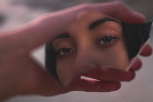 woman looking in broken mirror