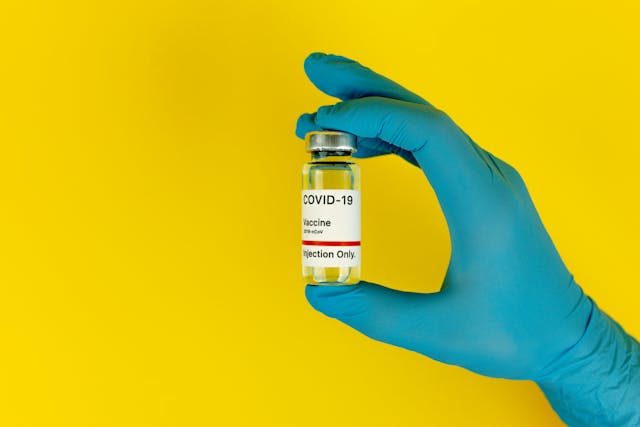 gloved hand holding a vial of vaccine