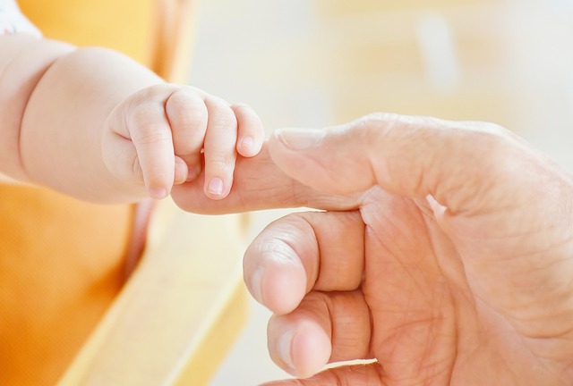 parent holding infant's hand