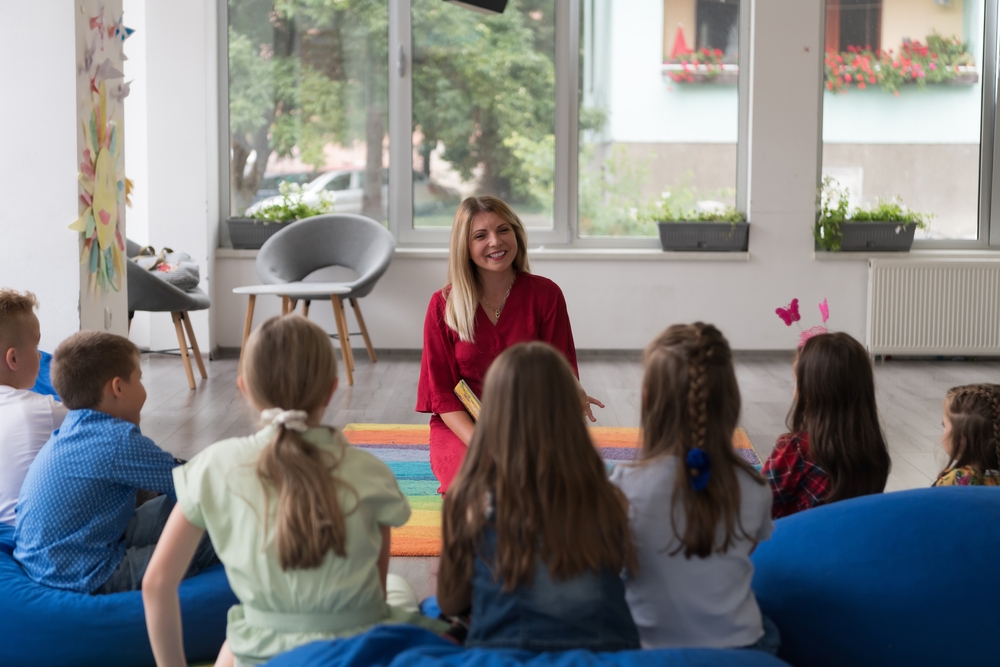 Reading time in an elementary school or kindergarten, a teacher reads a book to children in an elementary school or kindergarten. The concept of pre-school education. Selective focus