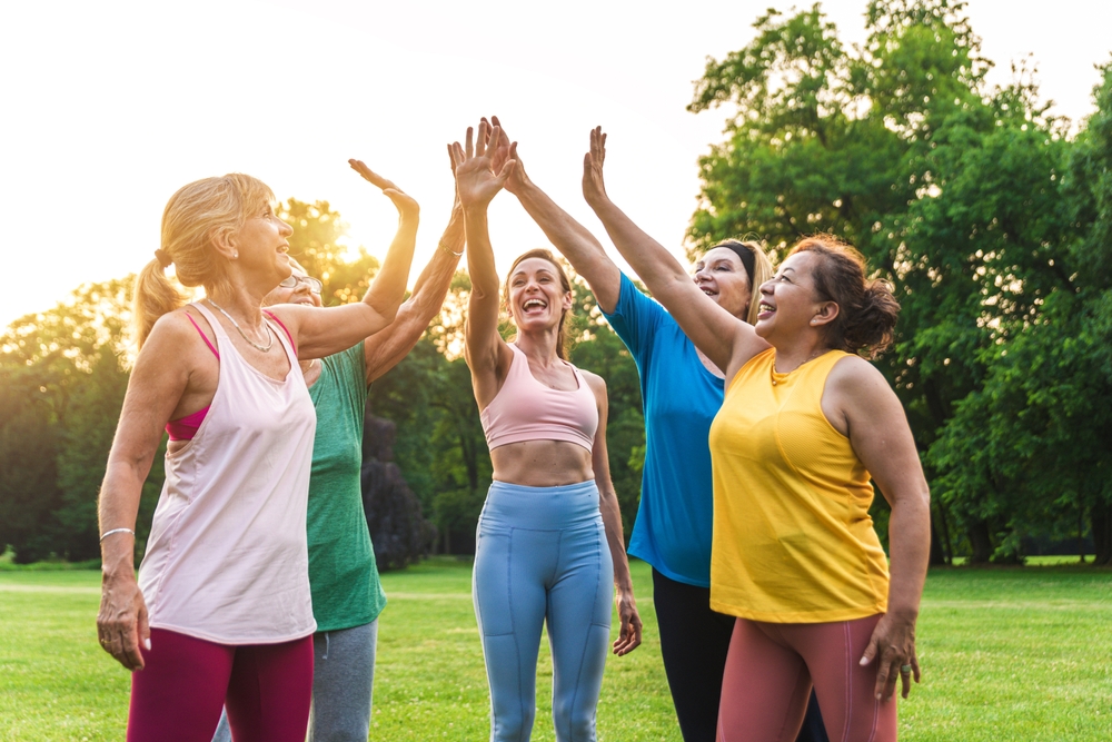 Multiethnic group of senior women training at park with fitness instructor - Active elderly people doing sport in the nature