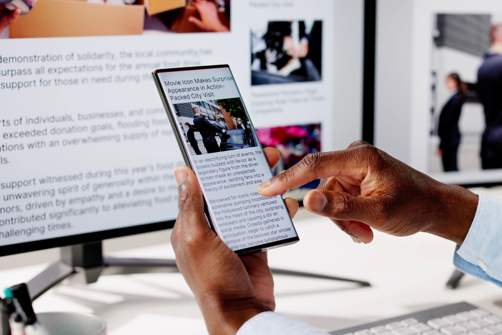 Watching Online News Article On Mobile Phone And Laptop. Electronic Newspaper