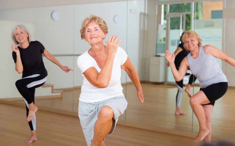 Active elderly lady visiting choreography class with group of women, learning modern dynamic dances. Concept of active lifestyle of senior generations