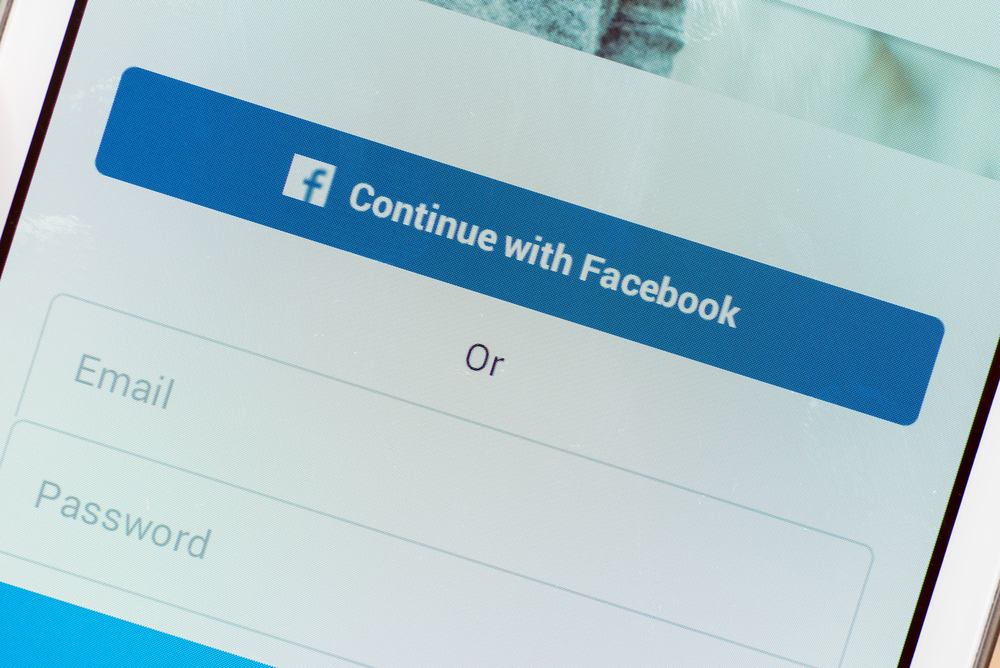 LVIV, UKRAINE - March 21, 2016: White Smart Phone with Log In Screen registration by Facebook Social Network account