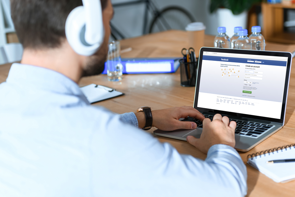 businessman using laptop with loaded facebook page
