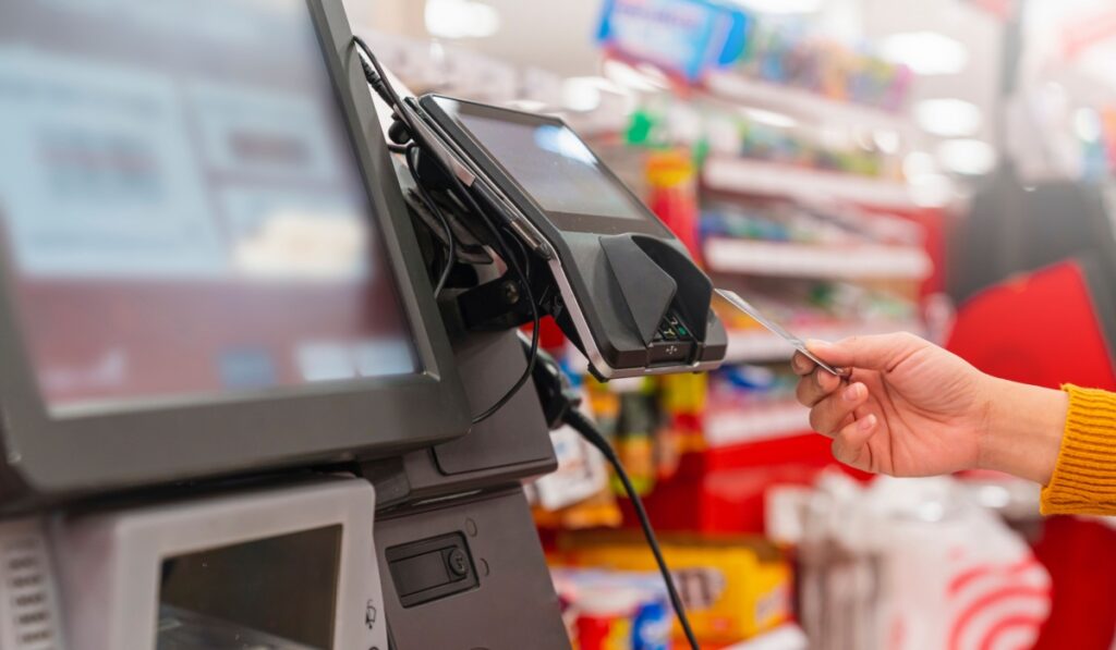 close up human female hand with pos cashier machine Retail, credit card payment service. Customer paying for order of cheese in grocery supermarket store sho