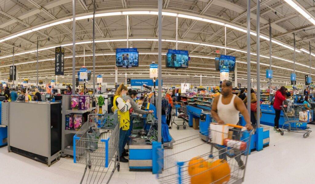 Checkout point at Walmart superstore, customers are out with purchases with carts,
