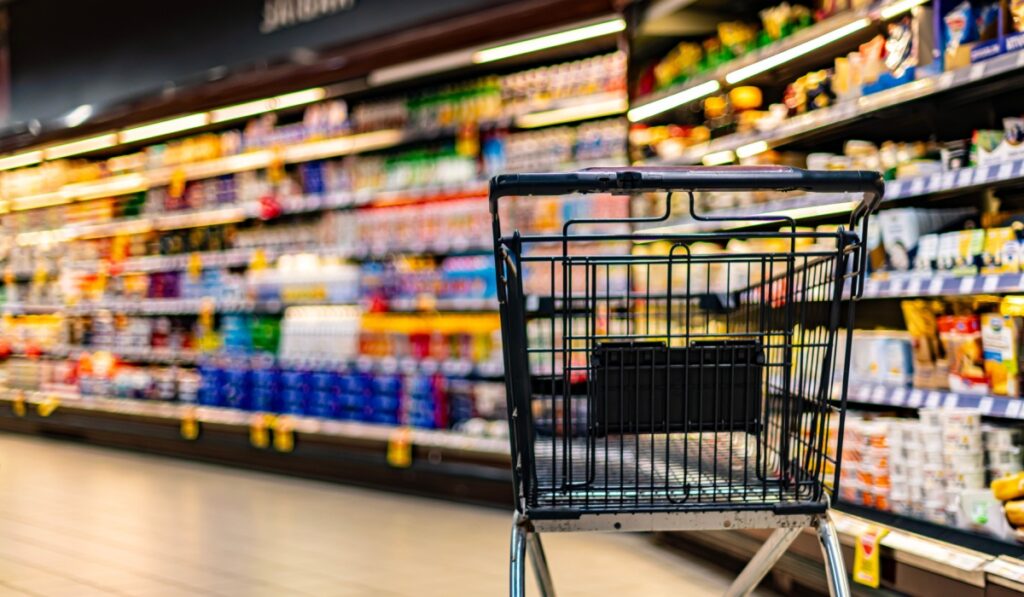 A shopping cart by a store shelf in a supermarket