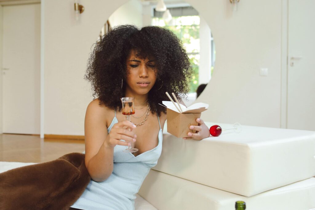 Woman in Blue Dress Holding a Takeaway and Glass Cup.