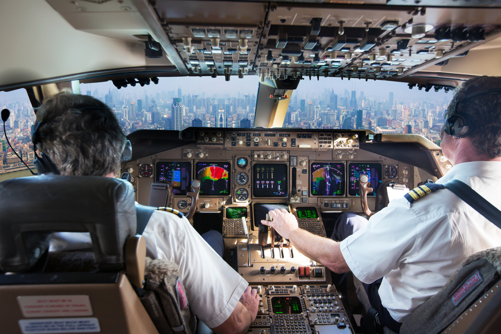 The cockpit of a modern passenger aircraft in flight. Pilots at work. A view from the cockpit to the skyscrapers of the business center of a big city.