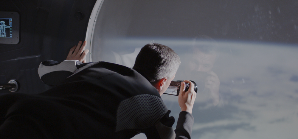Medium shot of a male astronaut filming Earth from a spaceship