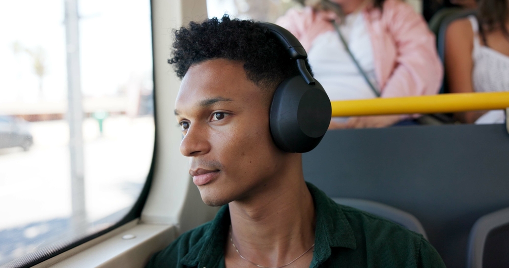 Bus, thinking and man with headphones for journey, commute and travel listening to music in city. Public transport service, student and person on vehicle for trip to university, college and radio