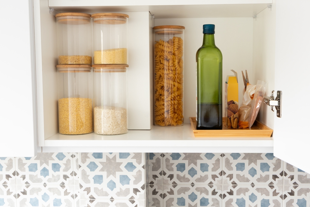 Organized kitchen pantry shelf with grains, olive oil bottle and pasta. Minimal modern kitchen interior