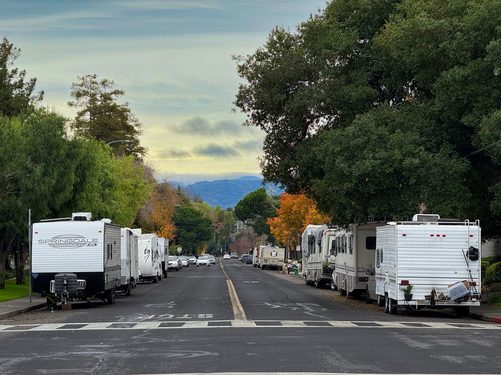 Homeless encampment along Independence Ave. Parked trailers, aging RV units, and personal belongings occupy a quiet neighborhood street - Mountain View, California, USA - December 25, 2025