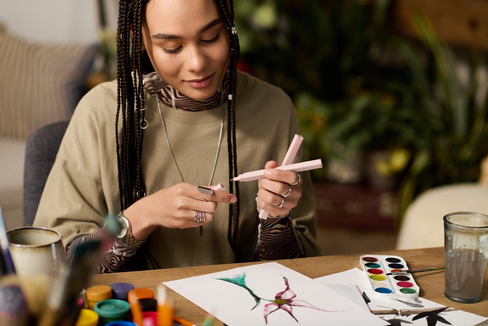 In a modern apartment, a young woman with braids joyfully paints colorful art, embracing creativity.