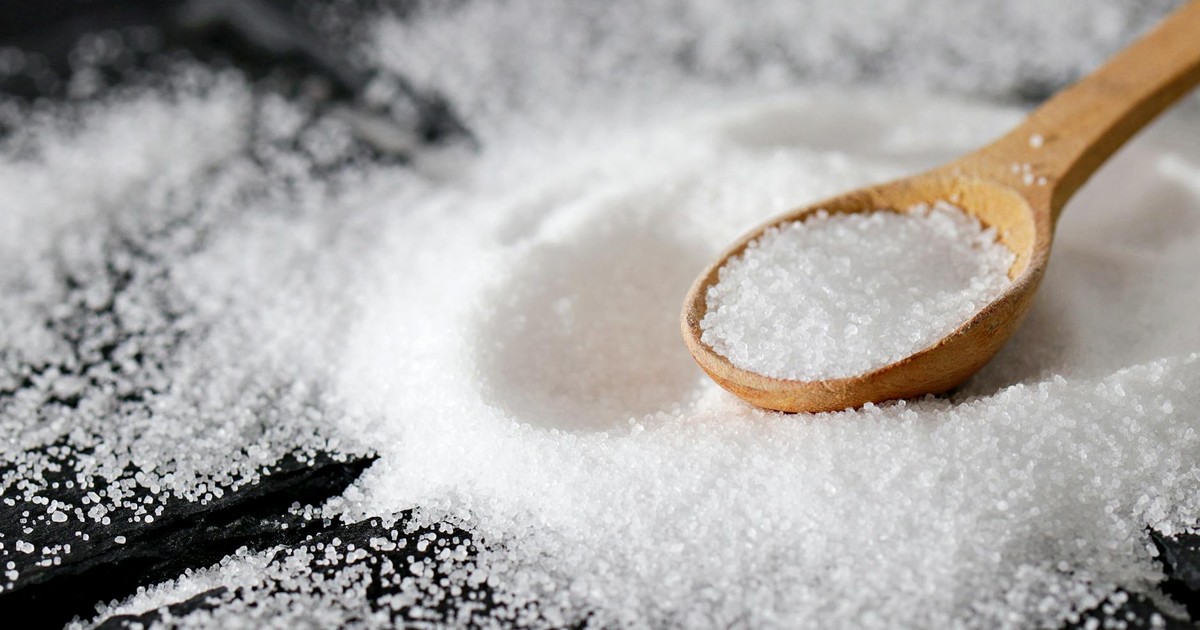 A close-up view of fine sea salt in a wooden spoon, perfect for culinary uses.