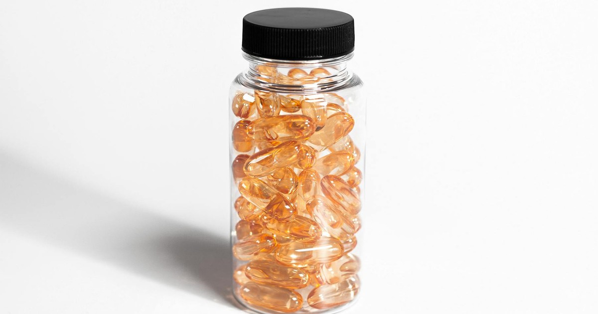A transparent bottle filled with amber capsules against a white background, showcasing health and nutrition.