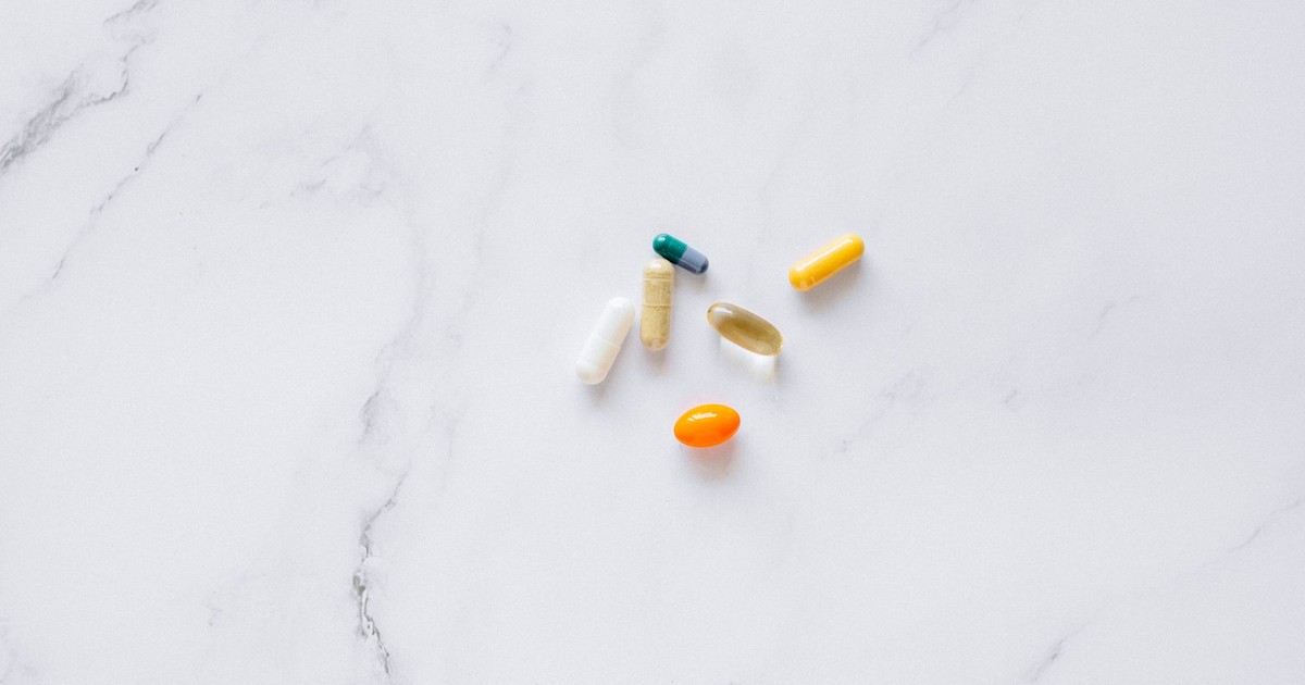 A variety of colorful pills arranged on a white marble surface, representing healthcare.