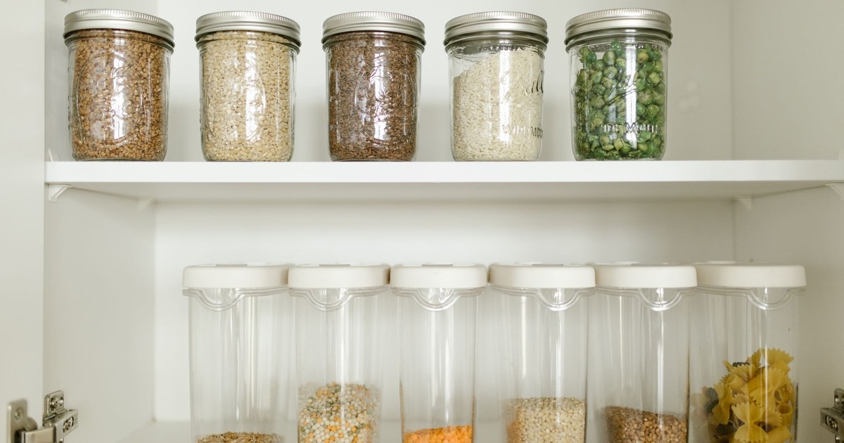 Neatly arranged pantry showcasing grains in glass jars and dry goods in plastic containers.